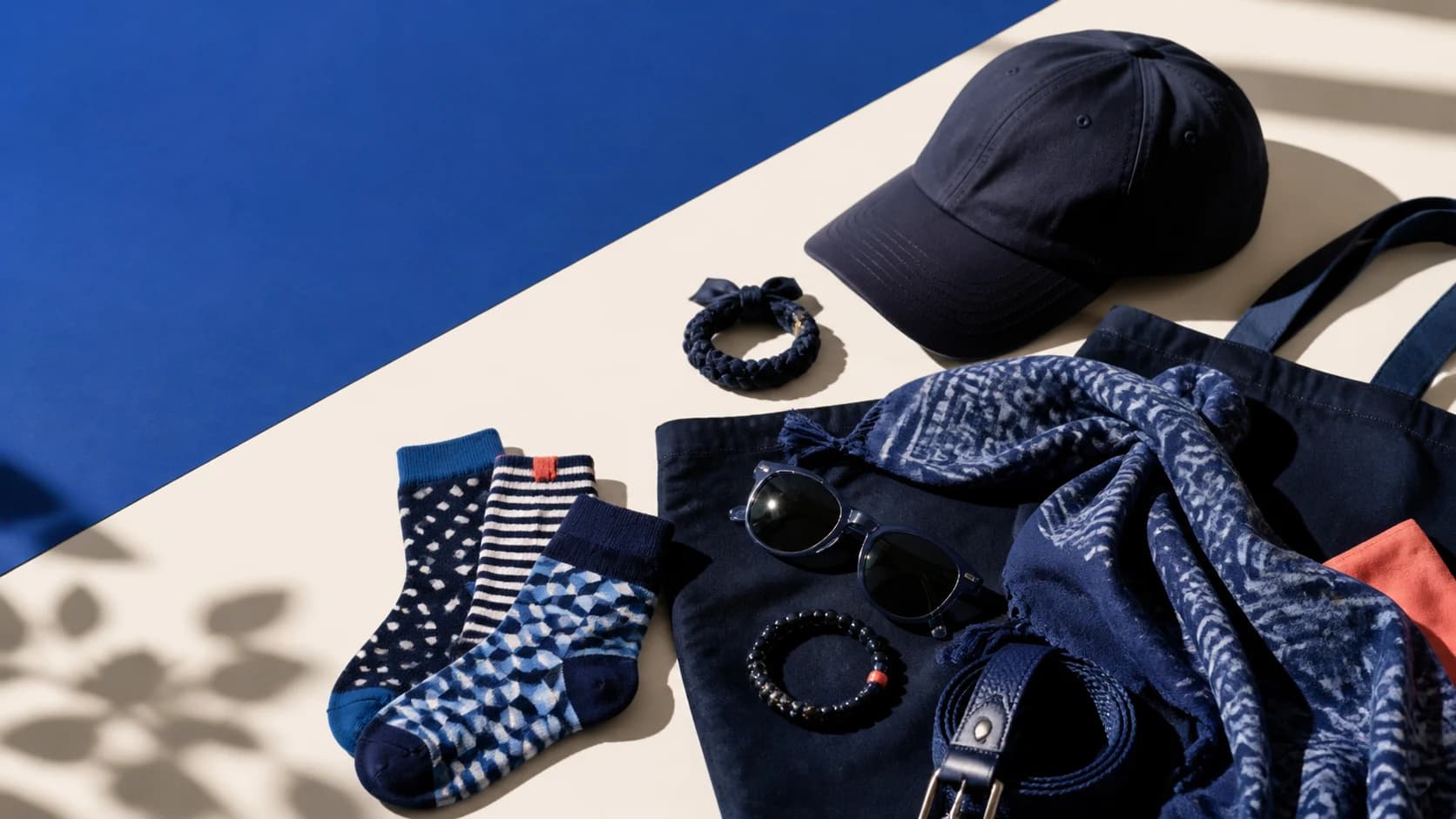 Caps, socks, scarf, belt, sunglasses and small accessories arranged in cobalt and cream